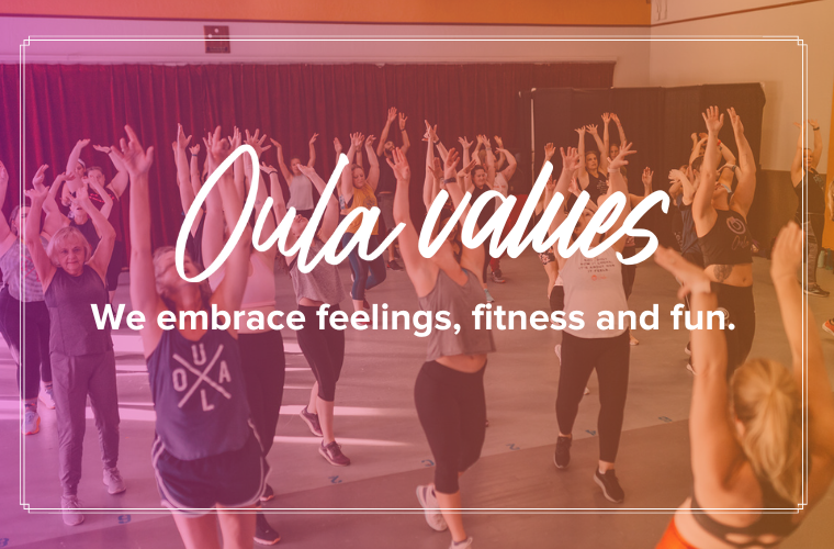Oula values: We embrace feelings, fitness and fun. A group of dancers with their hands and faces raised up.
